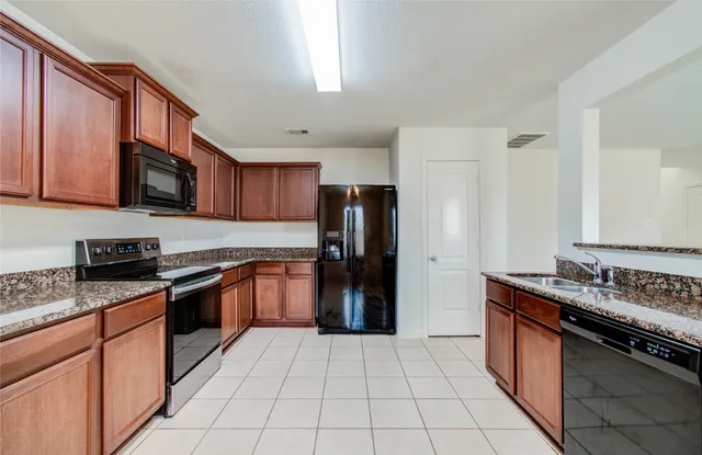 a kitchen with stainless steel appliances granite countertop a stove top oven a refrigerator and a sink