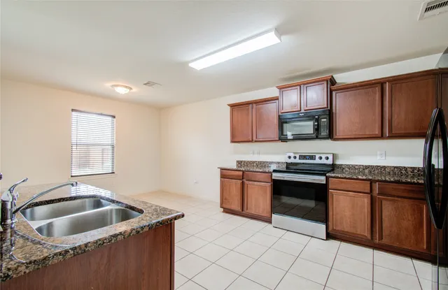 a kitchen with granite countertop a sink stove top oven and cabinets