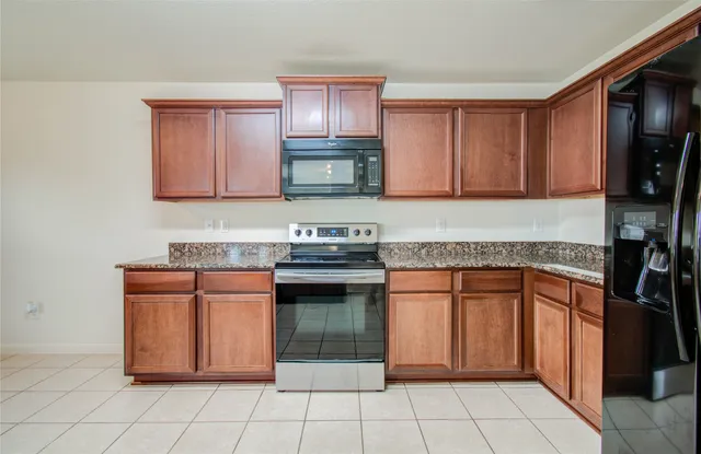 a kitchen with granite countertop a stove top oven microwave and cabinets