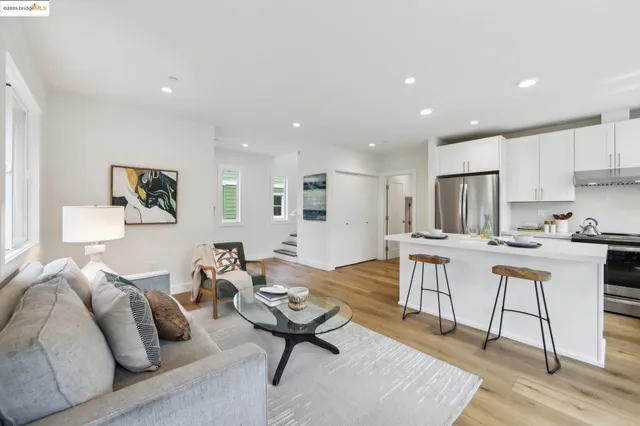 a living room with furniture kitchen view and a wooden floor