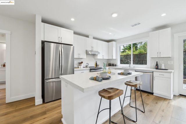 a kitchen with a refrigerator a stove a sink and a stove with white cabinets