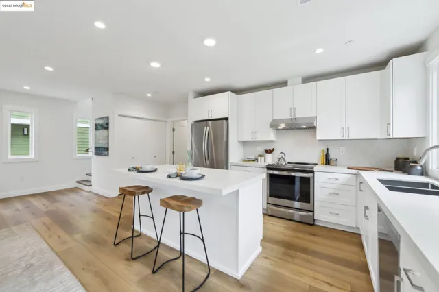 a kitchen with a stove a sink a stove a refrigerator and white cabinets with wooden floor