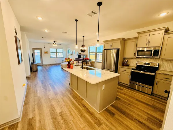 a kitchen with stainless steel appliances kitchen island granite countertop a stove refrigerator and cabinets
