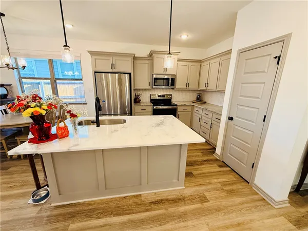 a kitchen with stainless steel appliances kitchen island granite countertop a sink refrigerator and microwave
