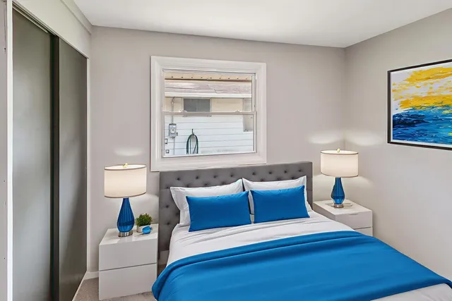 a bedroom with a bed and a lamp on dresser