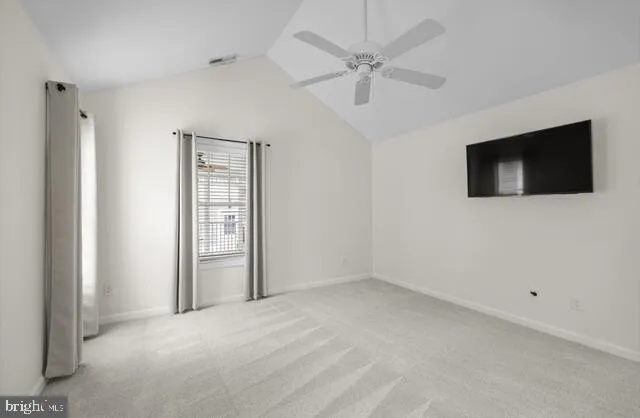 an empty room with a flat screen tv and a ceiling fan