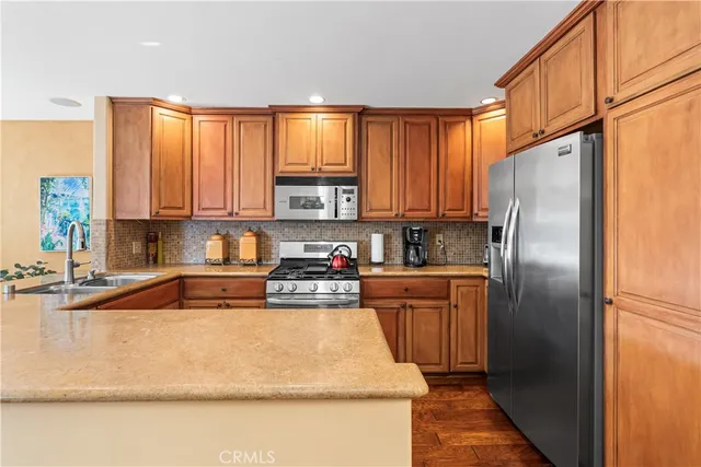 a kitchen with stainless steel appliances granite countertop a refrigerator a stove top oven a sink and dishwasher