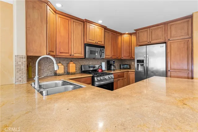 a kitchen with granite countertop a refrigerator a stove a sink and cabinets