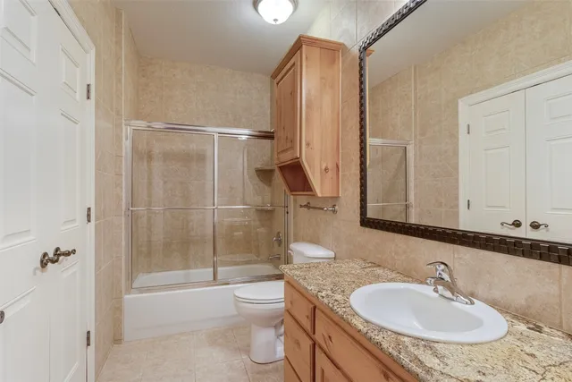 a bathroom with a granite countertop sink a toilet and shower