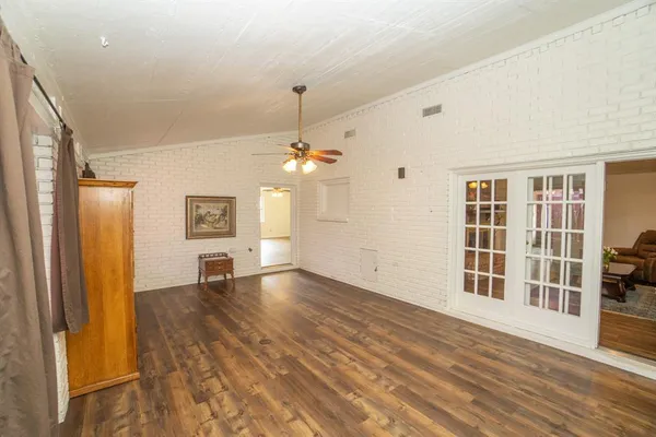 an empty room with wooden floor cabinet and windows