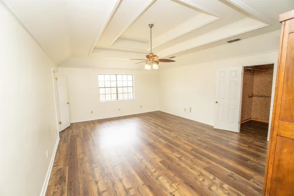 an empty room with wooden floor closet and windows