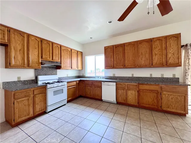 a large kitchen with granite countertop a stove sink and cabinets