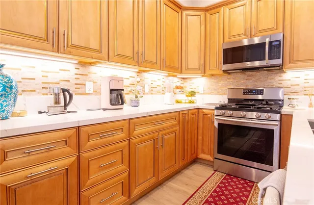 a kitchen with stainless steel appliances granite countertop a stove a sink and a microwave