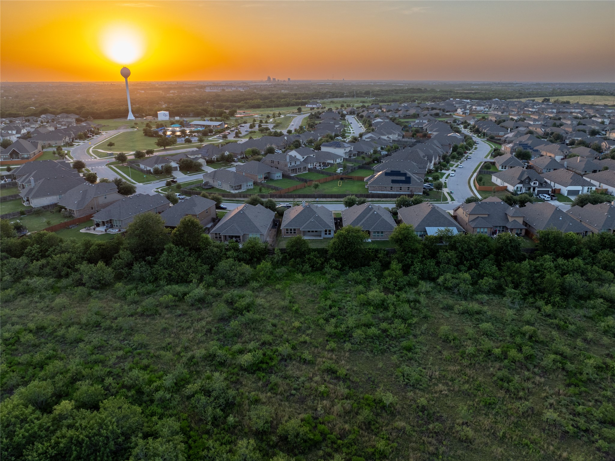 188 Nautical Loop Kyle, TX 78640 - Photo 32 of 38 An aerial perspective reveals a serene neighborhood nestled against a vibrant sunset, highlighting the community's layout.