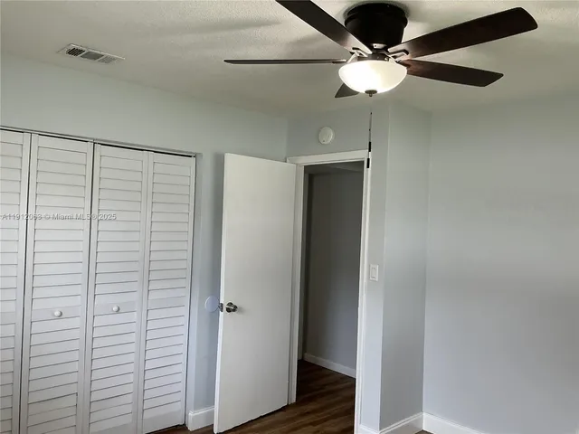 a view of a room with a ceiling fan and wooden floor