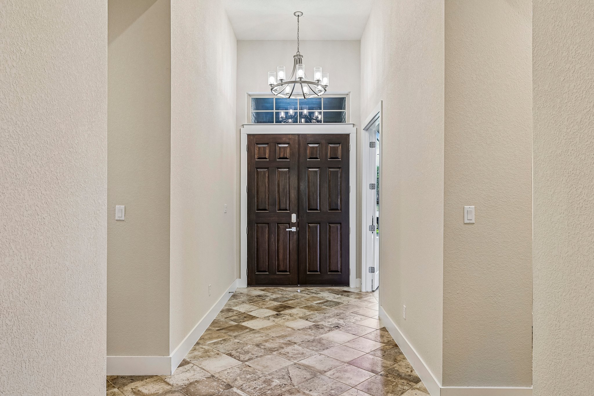 Grand double doors and a captivating chandelier welcome all who enter this elegant space.