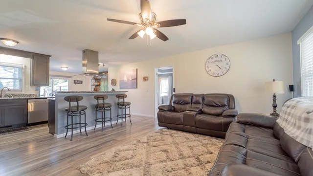 a living room with furniture a clock on wall and a dining table