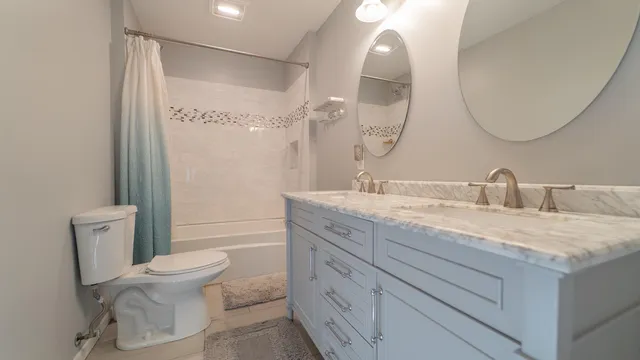 a bathroom with a granite countertop toilet a sink and a mirror