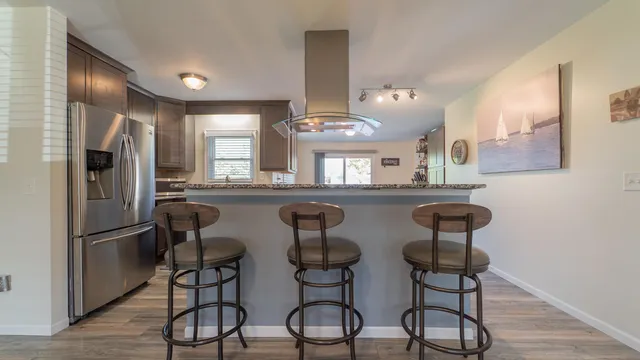 a kitchen with stainless steel appliances a dining table chairs cabinets and wooden floor