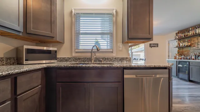 a kitchen with granite countertop a sink window and cabinets