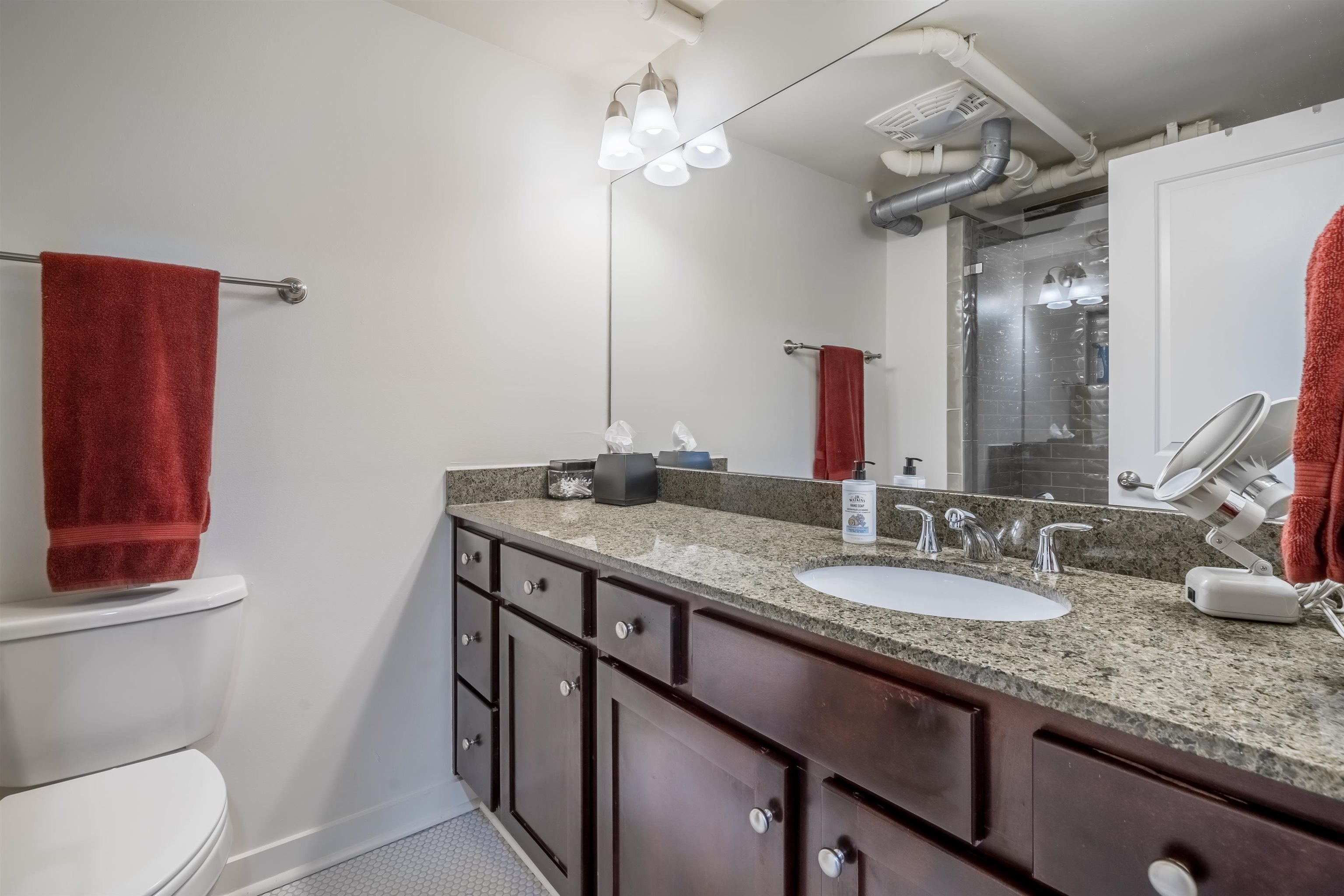 420 South Front Street, Unit 104 Memphis, TN 38103 - Photo 14 of 25 a bathroom with a granite countertop sink a toilet and a mirror