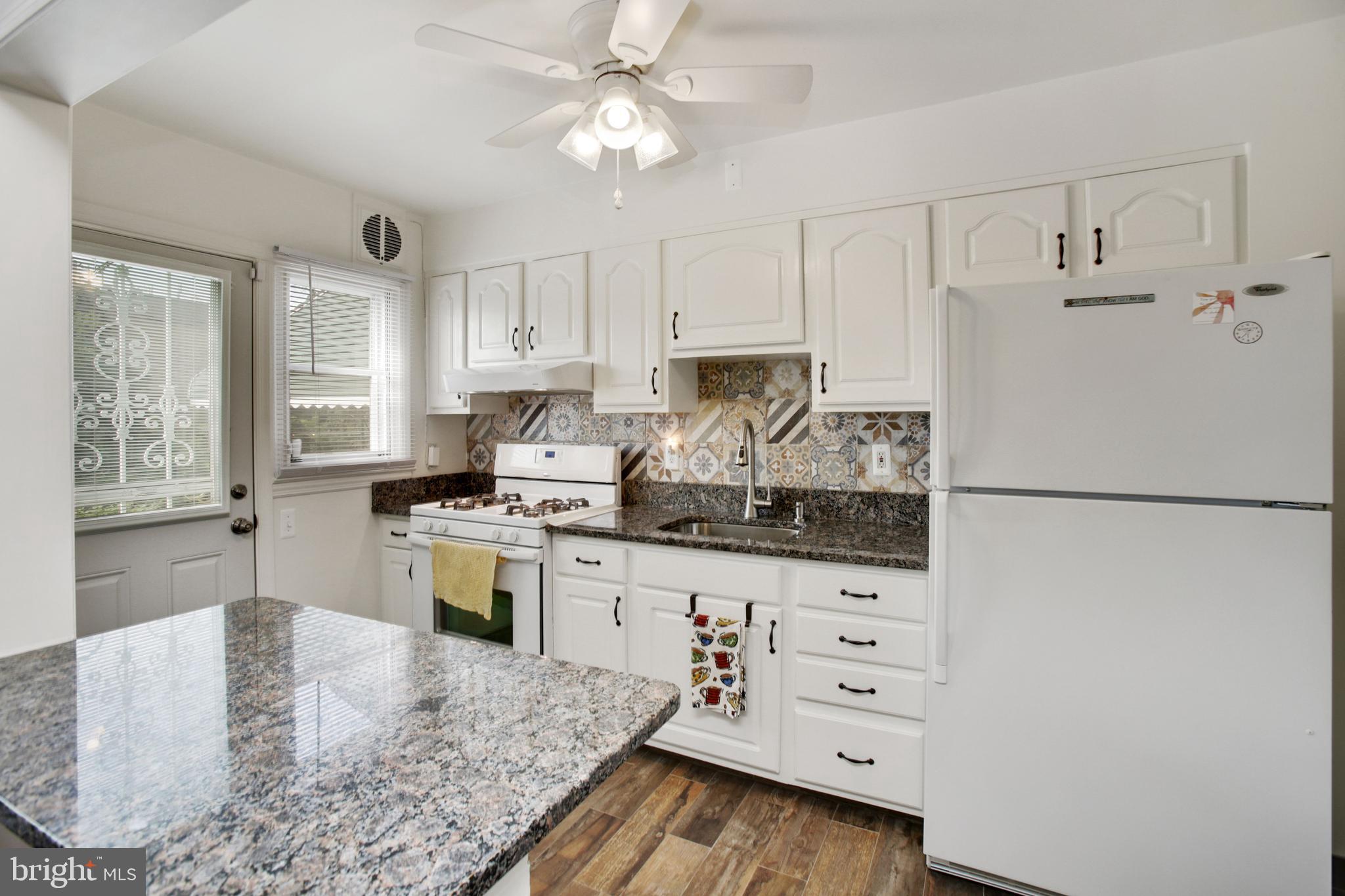 5021 West Hills Road Baltimore, MD 21229 - Photo 9 of 25 a kitchen with granite countertop a refrigerator a stove a sink a center island and cabinets