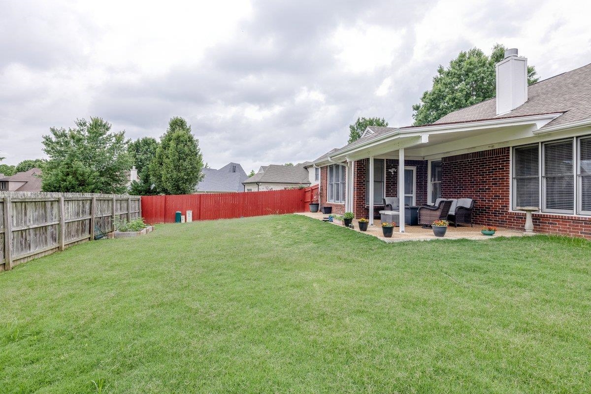 4840 Rainy Pass Road Collierville, TN 38017 - Photo 27 of 30 Expansive backyard featuring a large green lawn, covered patio, brick exterior, and a combination wood and red privacy fence