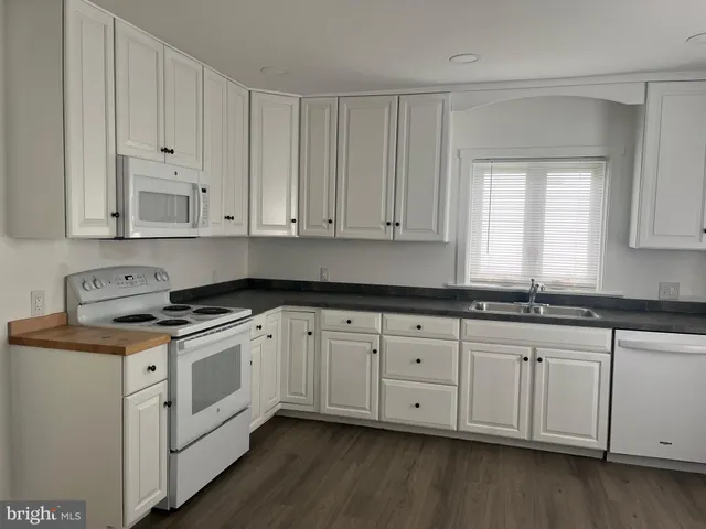 a kitchen with granite countertop white cabinets and a stove
