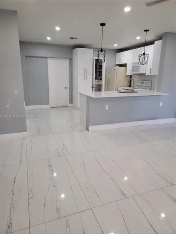 a large kitchen with stainless steel appliances kitchen island granite countertop a refrigerator a sink and a stove