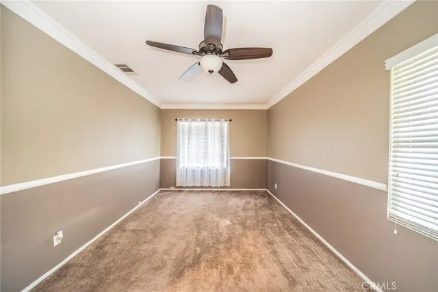 an empty room with a chandelier fan and windows