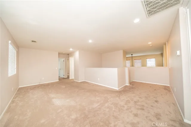 a view of an empty room with window and chandelier fan