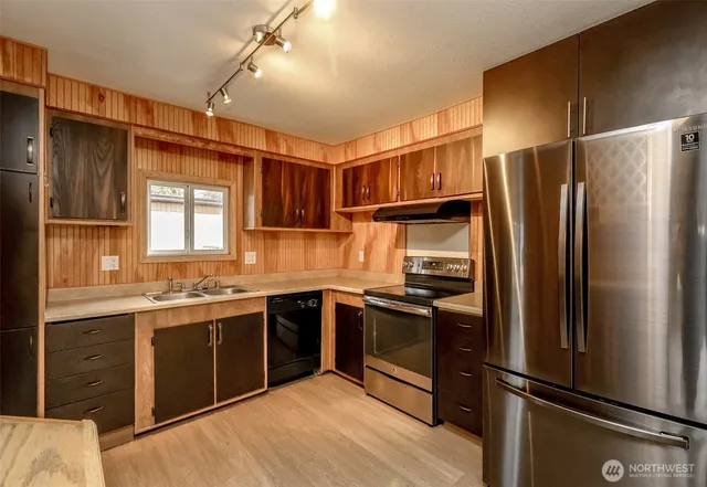 a kitchen with stainless steel appliances granite countertop a refrigerator a sink dishwasher a stove and white cabinets with wooden floor