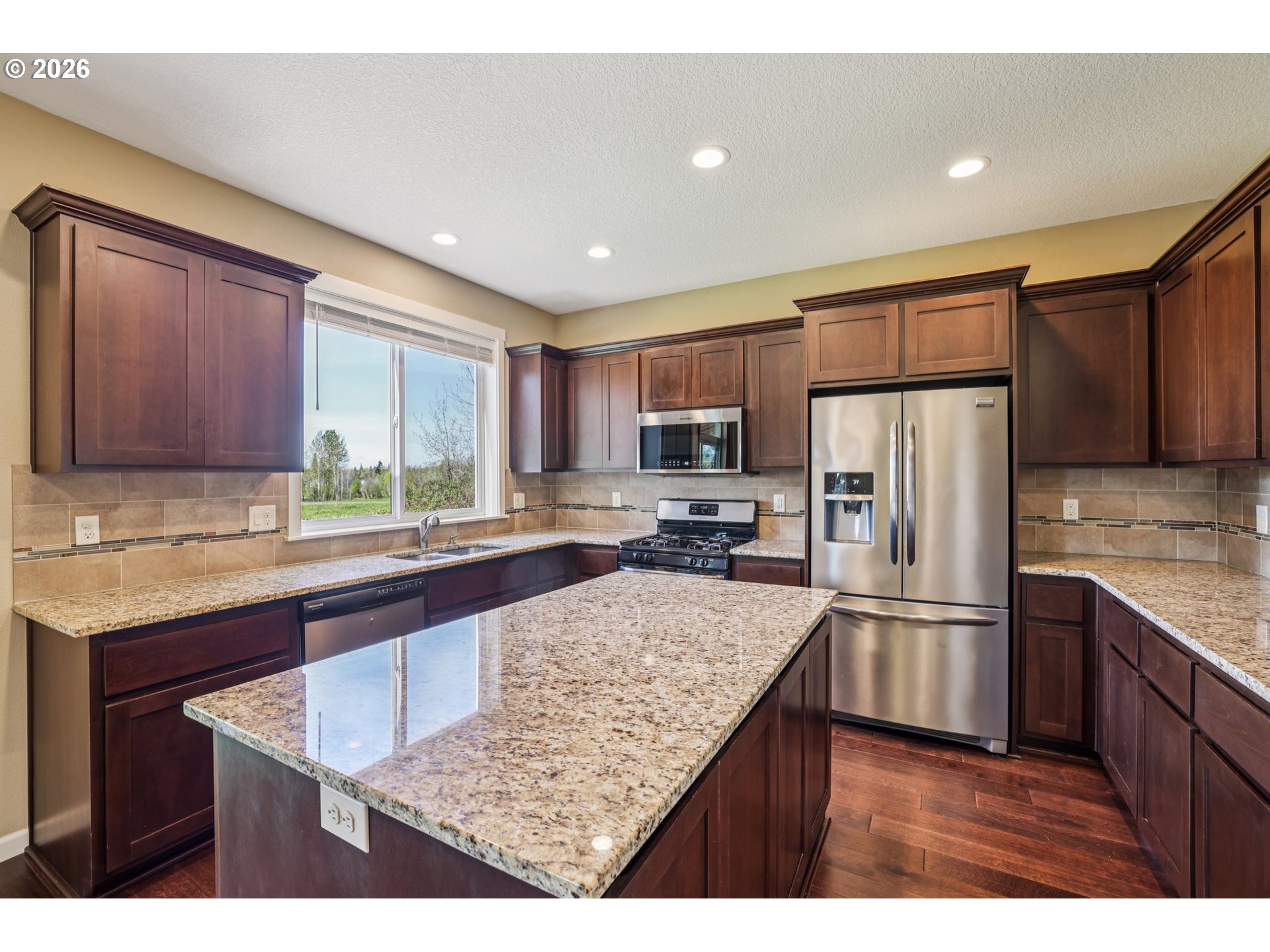 2117 Southeast Cochran Drive Gresham, OR 97080 - Photo 19 of 48 a kitchen with kitchen island granite countertop wooden cabinets a refrigerator and a sink