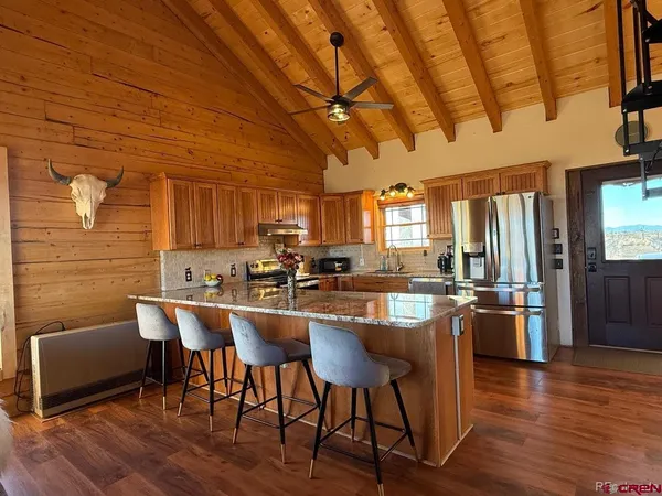 a kitchen with stainless steel appliances a dining table chairs and wooden floor