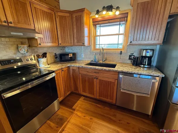 a kitchen with stainless steel appliances granite countertop wooden cabinets stove top oven and sink