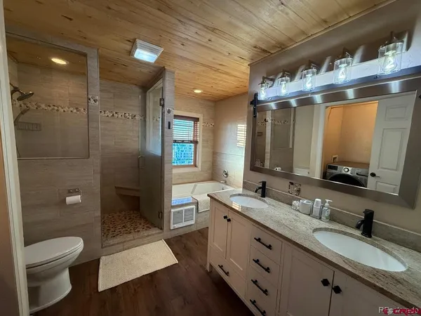 a spacious bathroom with a granite countertop sink toilet a mirror a vanity and shower