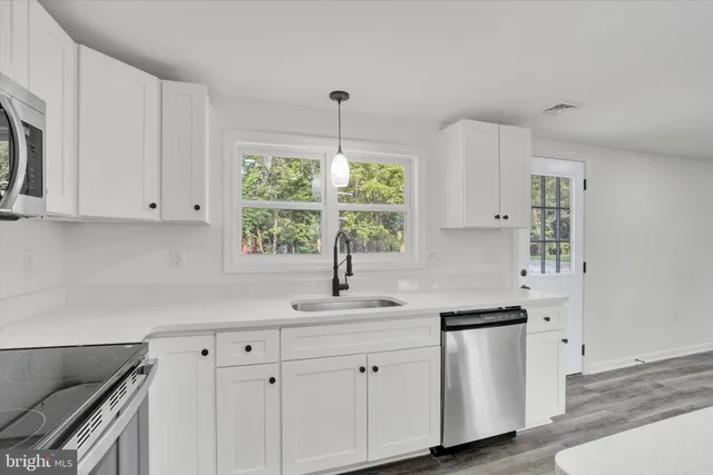 a kitchen with white cabinets white appliances and sink