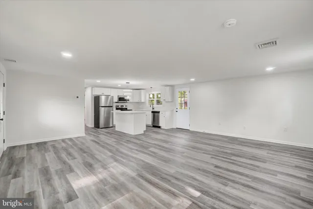 a view of a electric appliances in kitchen and empty room with wooden floor
