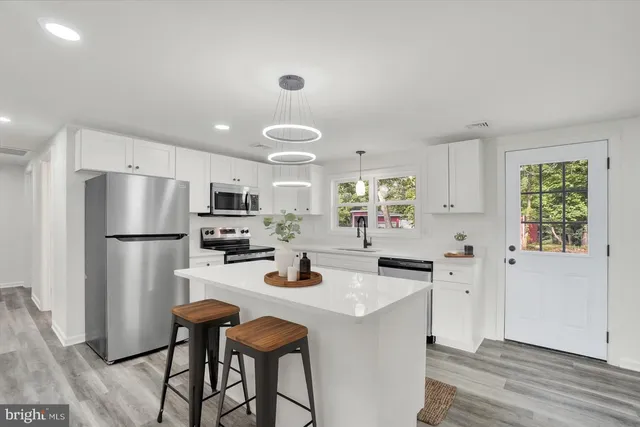 a kitchen with a refrigerator a stove a sink and dishwasher with wooden floor