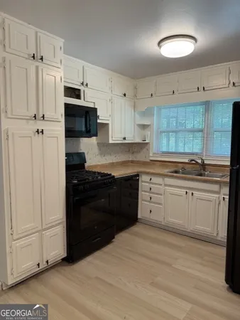 a kitchen with a refrigerator and white cabinets
