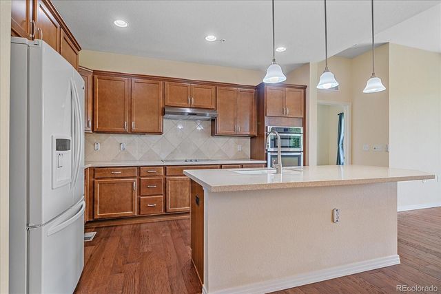 a kitchen with stainless steel appliances kitchen island granite countertop a stove a sink and a refrigerator