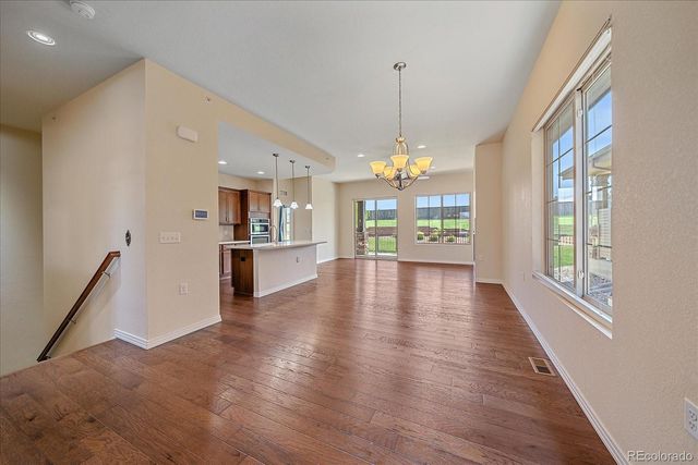 a view of an empty room with kitchen and window