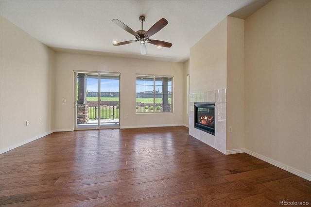 an empty room with wooden floor chandelier and windows