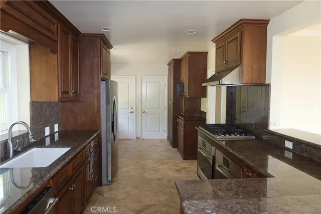a kitchen with stainless steel appliances granite countertop a sink stove and refrigerator