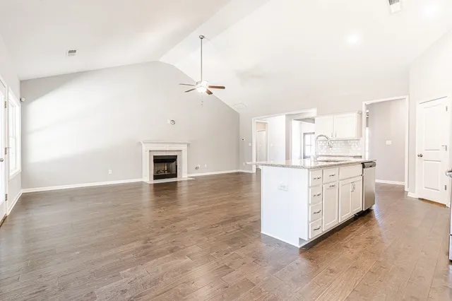 a view of a kitchen with a sink stove cabinets and empty room