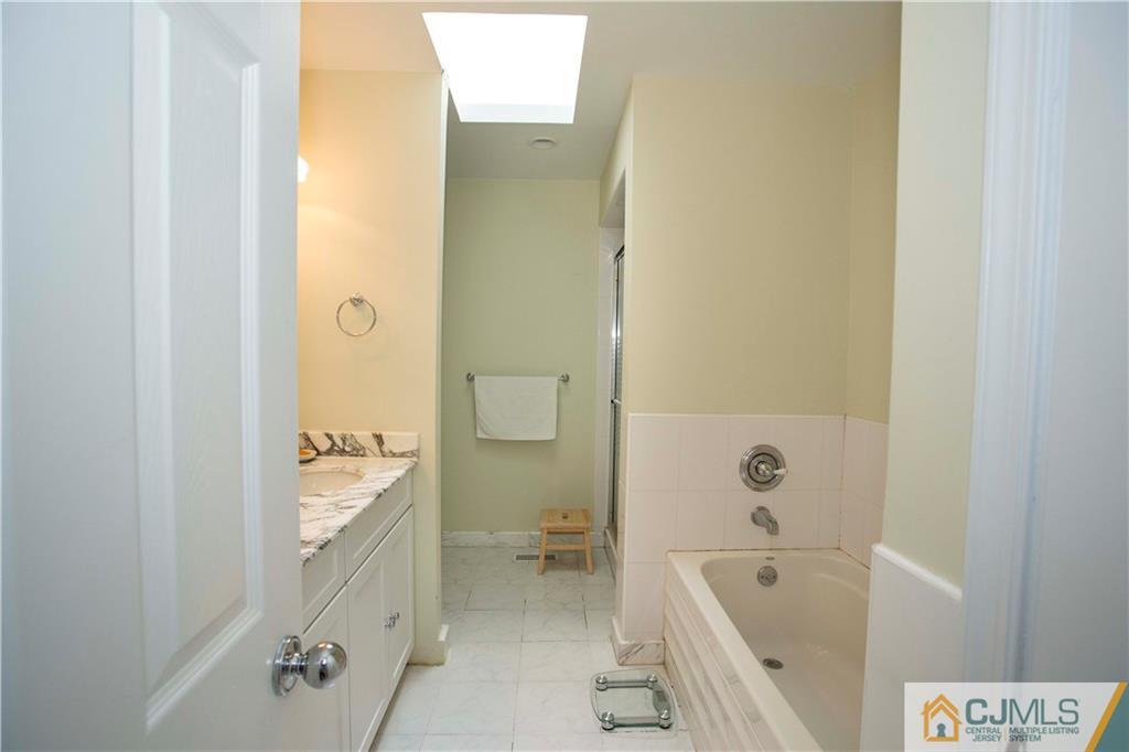 3806 Springbrook Drive Edison, NJ 08820 - Photo 13 of 22 a bathroom with a tub a sink and a large mirror