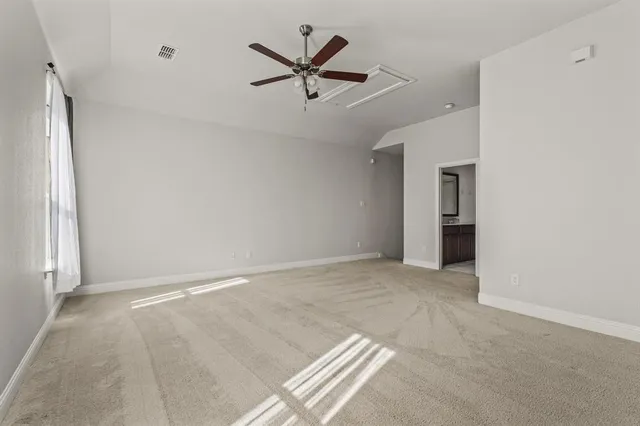 an empty room with ceiling fan and window