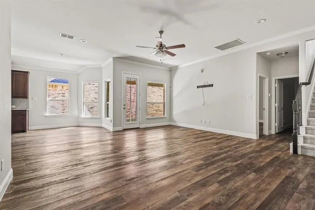 a view of an empty room with window and wooden floor