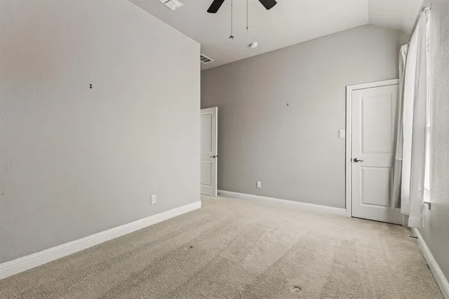 an empty room with a ceiling fan and window