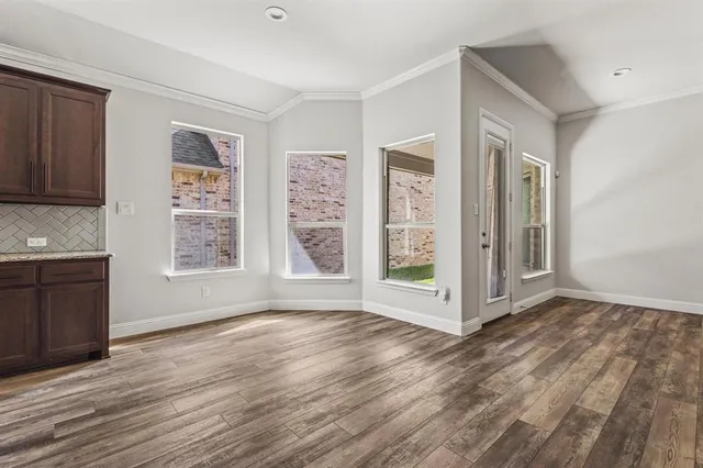a view of an empty room with window and wooden floor